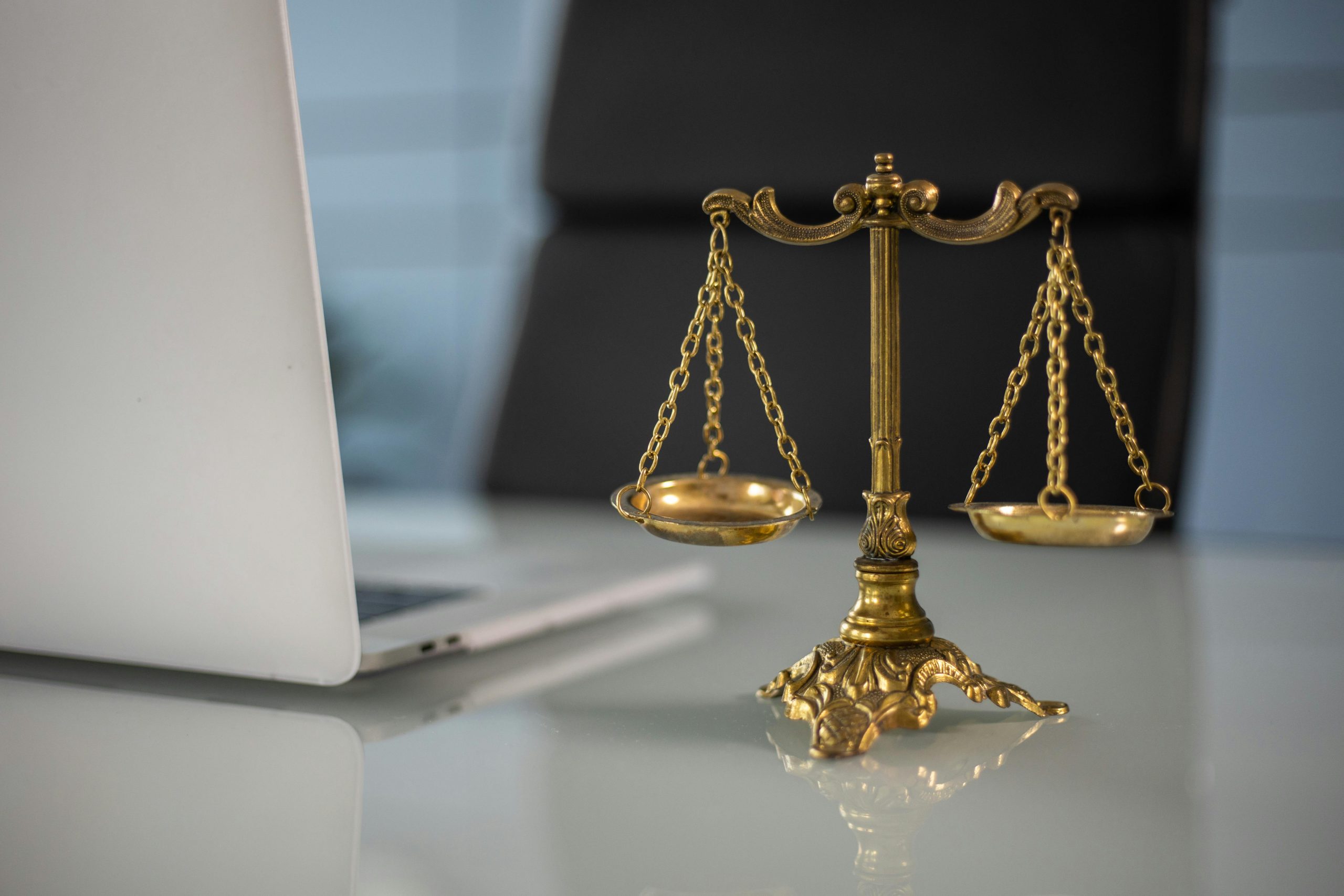 law scale figurine placed beside an open laptop on a desk